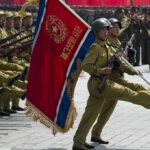 Soldiers marching with flag in military parade.