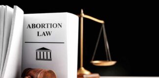 Gavel and abortion law book next to scales.