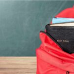 Red backpack with Bible and book inside.