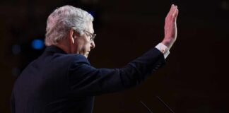 Man raising hand behind podium.