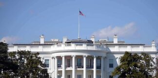 White House with American flag flying, daytime.