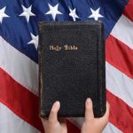Bishops Legally Challenge Government on Refugee Aid Funding Dispute Bible held in front of American flag.