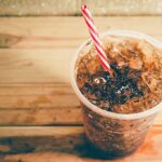 Sugary Drink Ban Sparks Health vs. Freedom Debate in SNAP Policy Cup of iced cola with striped straw.