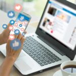Person using phone with social media reactions floating