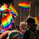 People holding rainbow flags at an outdoor gathering