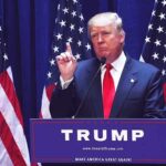 Decoding the Impact of Trump’s Tariff Strategy on U.S. Industries Man speaking at podium with American flags behind