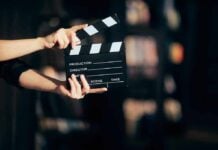 Hands holding a film clapperboard against a dark background.