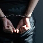 Heightened Threats for Political Figures: Tulsi Gabbard’s Concerning Experience Hands in handcuffs behind back in dark room.