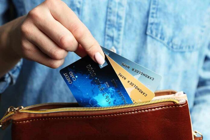 453955981 featured image Hand holding credit cards over a brown purse.