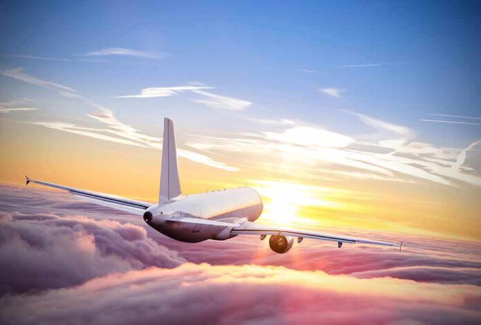 553131187 featured image Airplane flying above clouds during vibrant sunset