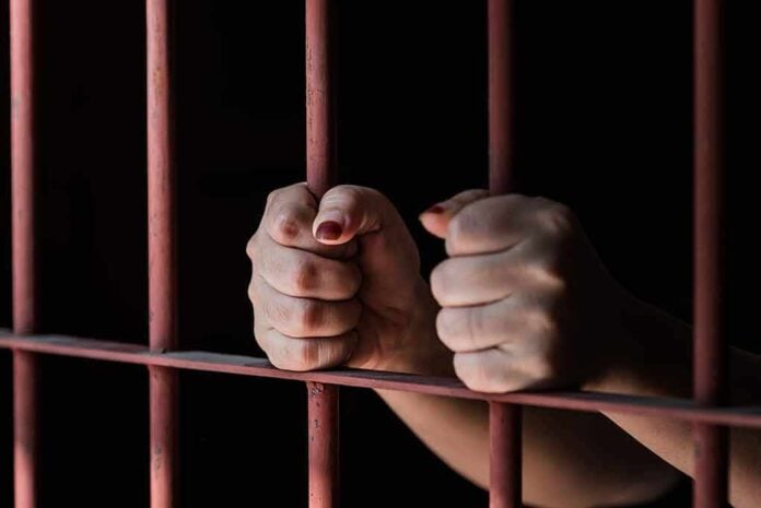 592930874 featured image Hands gripping rusty prison bars in darkness
