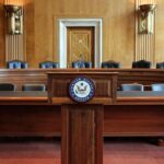 Mallory McMorrow Eyes U.S. Senate Run with Bold Change Agenda Empty U.S. Senate hearing room with wooden furniture.