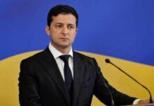Man in suit speaking at podium with microphones