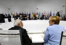 People seated around a large round table flags behind