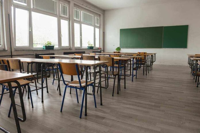 Empty classroom with desks chairs window and chalkboard