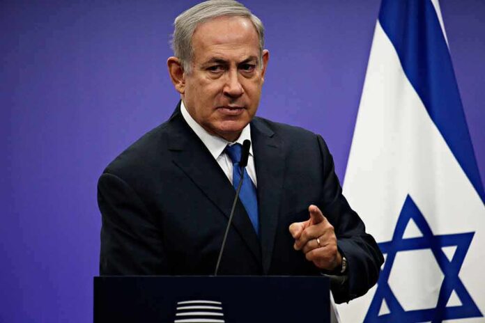1042782061 featured image Man in suit giving speech in front of Israeli flag.