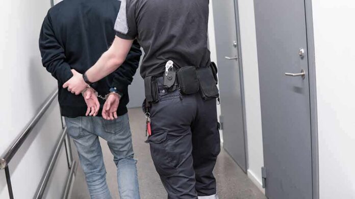 1082126789 featured image Officer escorting handcuffed person down hallway
