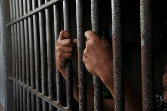 2452368639 featured image Hands gripping jail cell bars