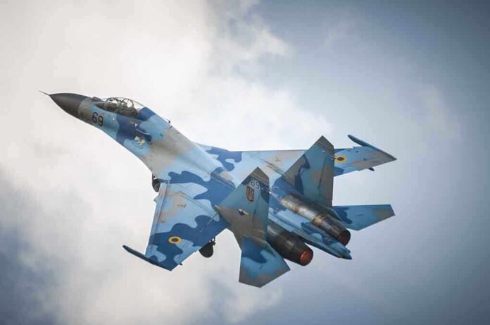 shutterstock_190311434.jpg A blue camouflage fighter jet performing an aerial maneuver against a cloudy sky