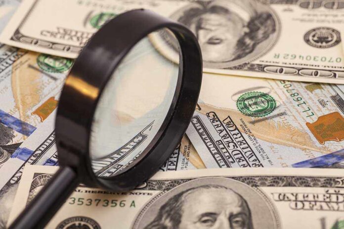 A magnifying glass resting on a pile of US dollar bills