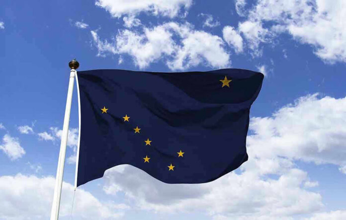 Alaska state flag flying against a blue sky.