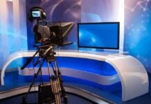 Television studio setup with a camera and monitor on a modern desk