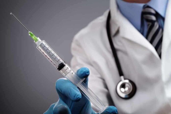 A doctor holding a syringe with a stethoscope around their neck