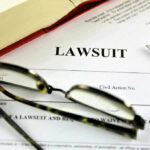 Lawsuit paperwork with glasses, pen, and an open book.