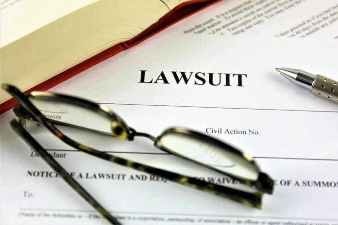 775833220 Lawsuit paperwork with glasses, pen, and an open book.