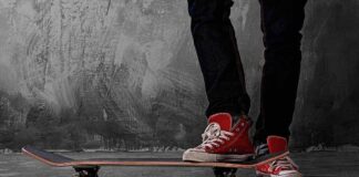Person standing on a skateboard wearing red sneakers