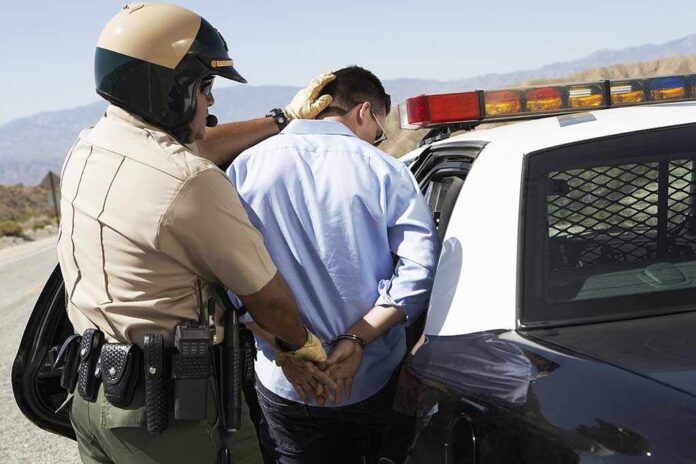 shutterstock_144637685.jpg Police officer arresting a suspect near a patrol car