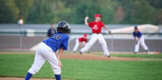 Young baseball player in blue uniform preparing to run on the field