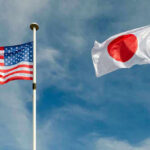 USA and Japan flags flying on flagpoles.
