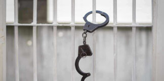 Handcuffs hanging on a barred window.