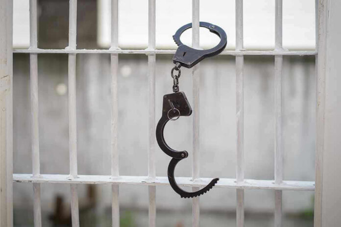 Handcuffs hanging on a barred window.