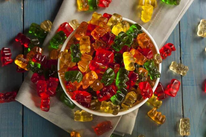 A bowl filled with colorful gummy bears surrounded by scattered candies