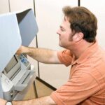 A man using an electronic voting machine in a privacy booth