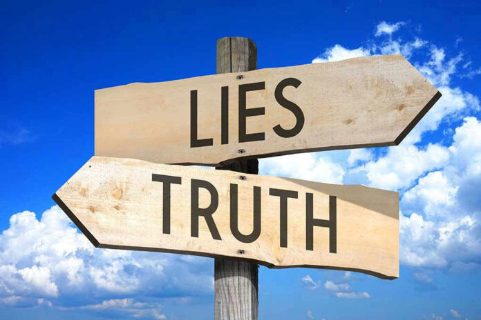 Signs pointing to Lies and Truth against sky.
