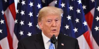 A man speaking at a podium with American flags in the background
