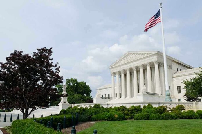 The U.S. Supreme Court building with an American flag and landscaped grounds