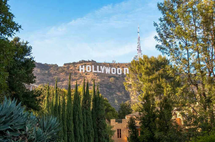 Hollywood sign on hill surrounded by trees and buildings.