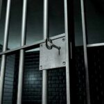 Close-up of a locked prison gate with metal bars