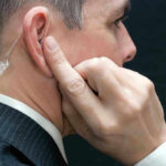 Agent’s Shocking BETRAYAL–Scandal Caught on VIDEO Man wearing an earpiece, touching his ear.