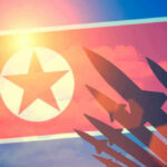 NEW North Korea’s Missile Blitz–At it AGAIN North Korean flag with missile silhouettes.