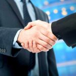 Two business professionals shaking hands in a corporate setting