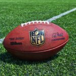 Airport Trap Costs NFL Starter Tens of Millions An NFL football resting on a green grass field