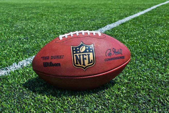 An NFL football resting on a green grass field