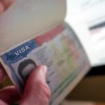 A hand holding a passport open to a visa page