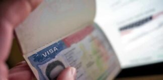 A hand holding a passport open to a visa page