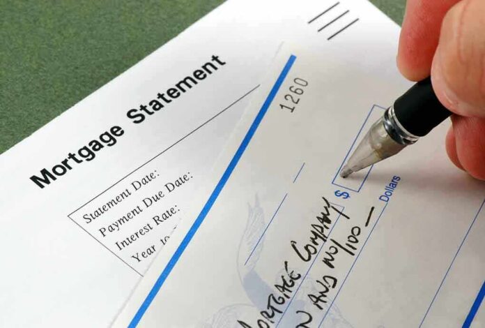 A person writing a check on a mortgage statement